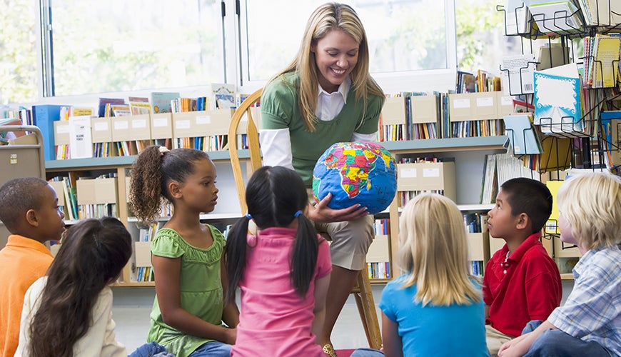 teacher showing map of world to children